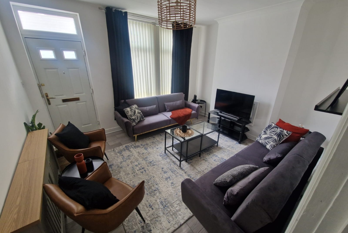 TV lounge with a sofa set and leather chairs by hmh stays