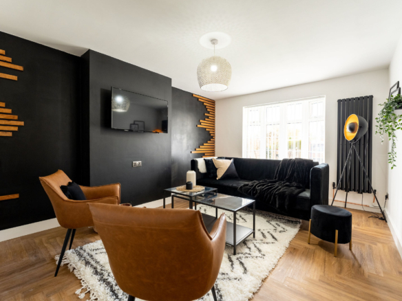 TV lounge with light brown leather chairs and having black velvet sofa in the property of link road by hmh stays